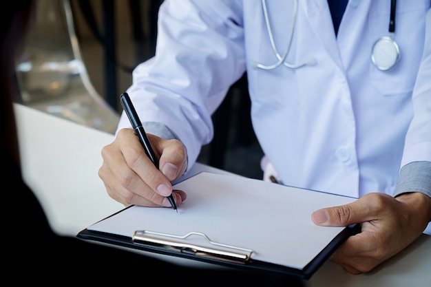 Patient listening intently to a male doctor explaining patient symptoms or asking a question as they discuss paperwork together in a consultation