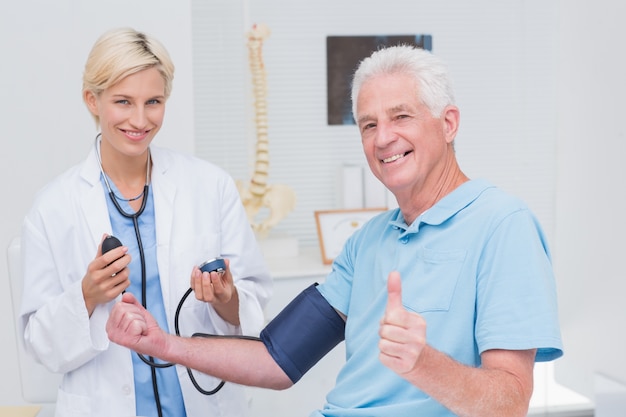 Patient showing thumbs up while doctor checking his blood pressure