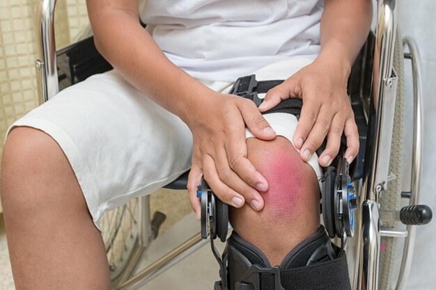 Patient sitting in wheelchair suffers from knee pain. 