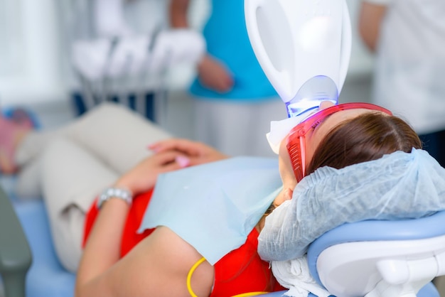 The patient undergoes a procedure for teeth whitening with an ultraviolet lamp