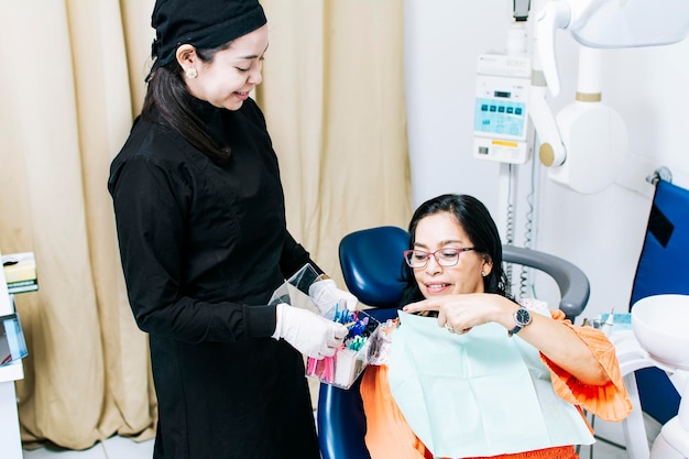 Patient with dentist choosing dental braces Dentist with patient choosing metal braces Patient with dentist choosing rubber band