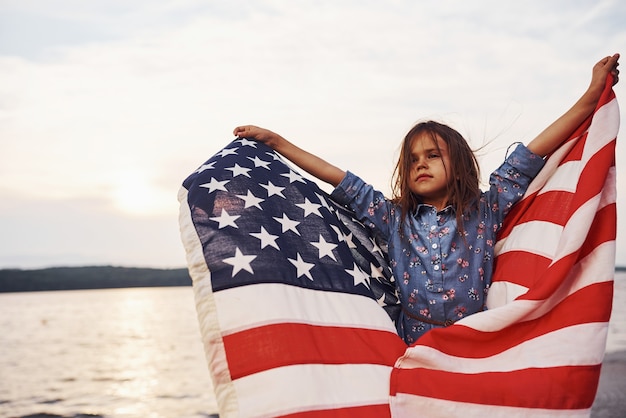 Patriotic female kid with American Flag in hands