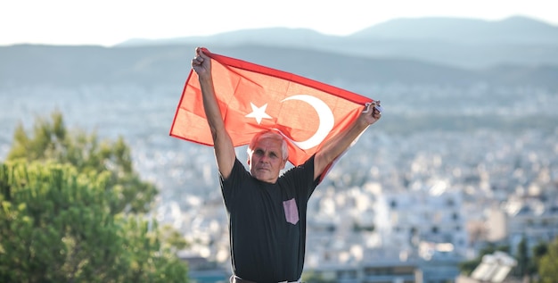 Patriotic senior man celebrates Turkish independence day with a national flag in his hands Constitution and Citizenship Day