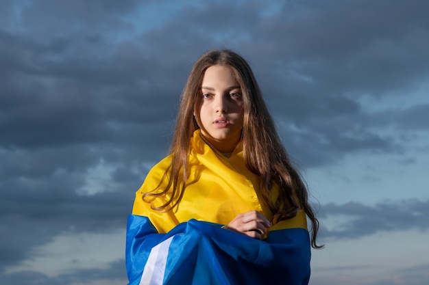 Patriotic teen ukrainian girl with national flag of independent ukraine