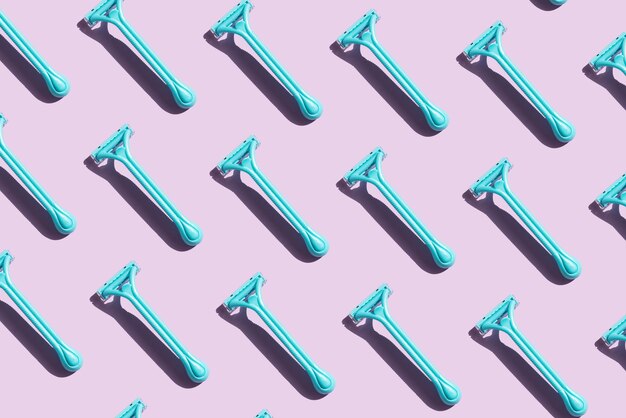 Photo pattern of blue razors with contrast shadows on a purple background