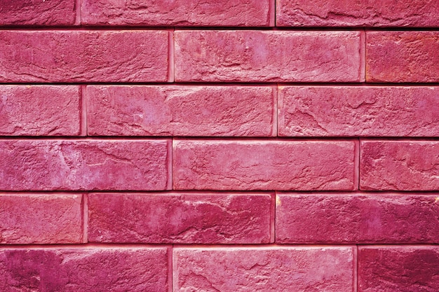 Pattern of decorative pink slate stone wall surface as a background toned in viva magenta trend color of the year 2023