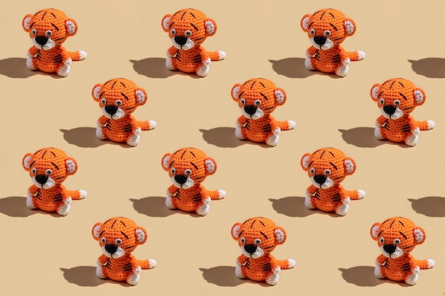 Pattern from Christmas toys. Knitted tiger cubs on a yellow background. Merry Christmas.