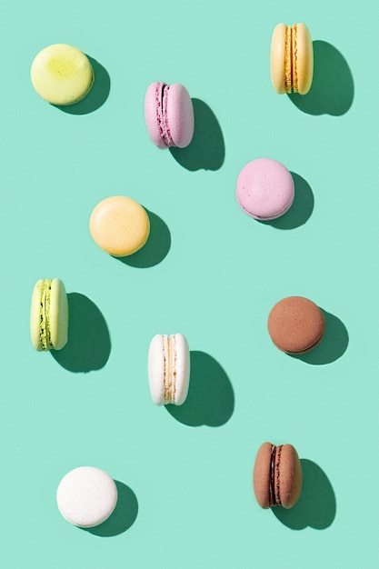 Pattern from different cake macaroons on green multi colored french biscuit macarons