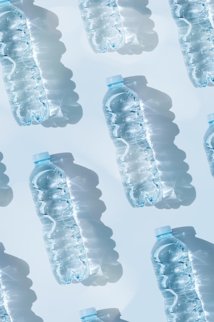 Pattern from Plastic bottles with water at sunlight with beautiful sun shadow on blue background