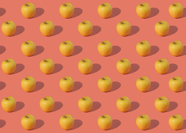 Pattern of juicy yellow apples on a pink background