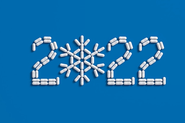 A pattern of many pills scattered on a blue background in the form of figures 2021. 3D illustration.