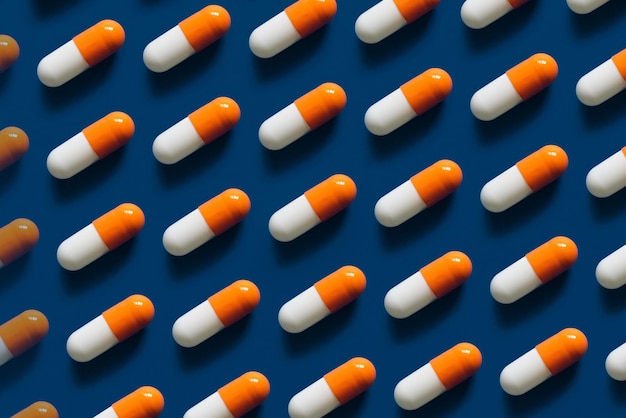 Pattern of orange and white capsules or pills arranged in a diagonal grid on a blue background