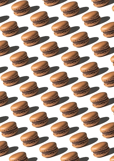 Pattern with chocolate macarons on white background