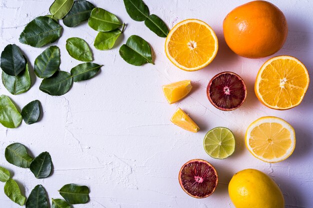 Pattern with raw fresh citrus fruit - yellow and red orange fruit, lemon, lime and lime leaves.