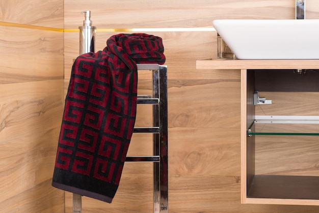 A patterned red dark blue towel on a rack in a bathroom