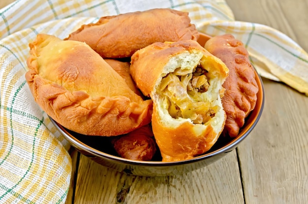 Patties fried with cabbage and meat in the dish, napkin on a wooden boards background