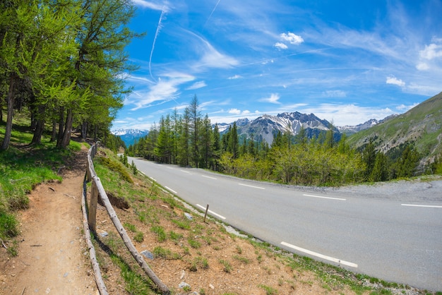 Paved two lane road in scenic alpine landscape and moody sky, fisheye view. Summer adventure and roadtrip at Col d'Izoard, France.