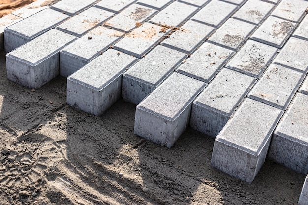 Pavement repair and laying of paving slabs on the walkway, stacked tile cubes on the background. Laying paving slabs in the pedestrian zone of the city, sand filling. Road tiles and curbs.