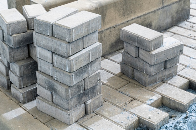 Pavement repair and laying of paving slabs on the walkway, stacked tile cubes on the background. Laying paving slabs in the pedestrian zone of the city, sand filling. Road tiles and curbs.