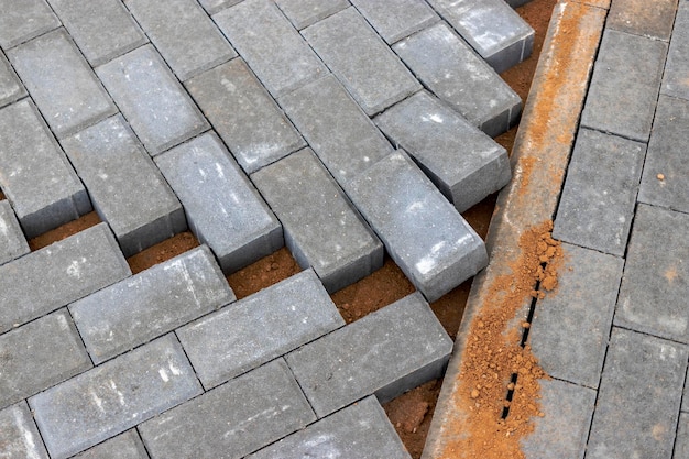 Pavement repairs and paving slabs laying on the prepared surface with tile cubes in the background Laying paving slabs in the pedestrian zone of the city Paving slabs and curbs