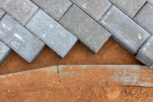 Pavement repairs and paving slabs laying on the prepared surface with tile cubes in the background Laying paving slabs in the pedestrian zone of the city Paving slabs and curbs