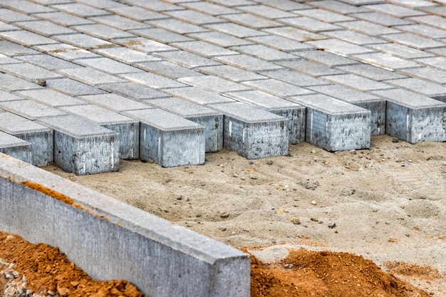 Pavement repairs and paving slabs laying on the prepared surface with tile cubes in the background Laying paving slabs in the pedestrian zone of the city Paving slabs and curbs