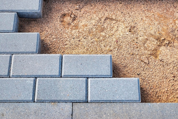 Pavement repairs and paving slabs laying on the prepared surface with tile cubes in the background Laying paving slabs in the pedestrian zone of the city Paving slabs and curbs