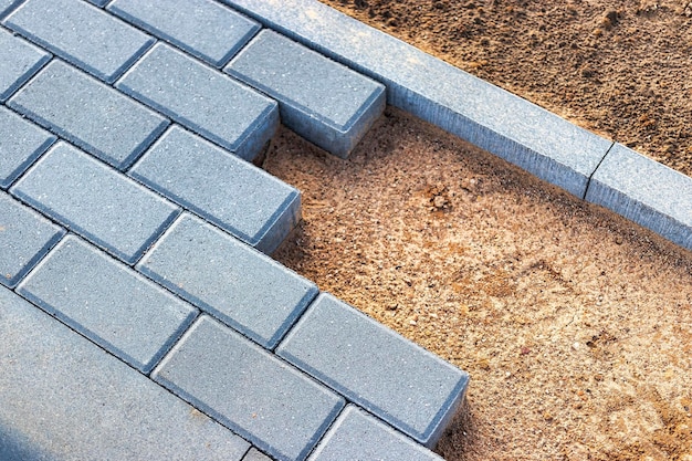 Pavement repairs and paving slabs laying on the prepared surface, with tile cubes in the background. Laying paving slabs in the pedestrian zone of the city. Paving slabs and curbs.