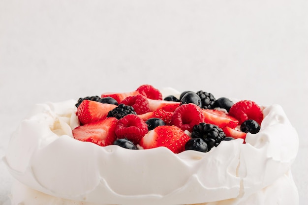 Pavlova meringue cake with fresh berries on white background