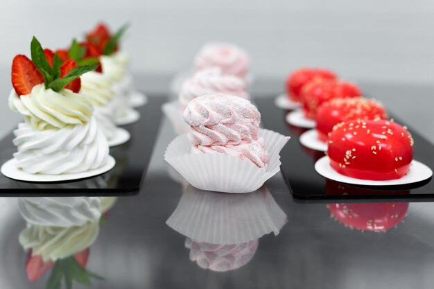 Pavlova meringue, marshmallows and mousse cake on the table in the pastry shop.