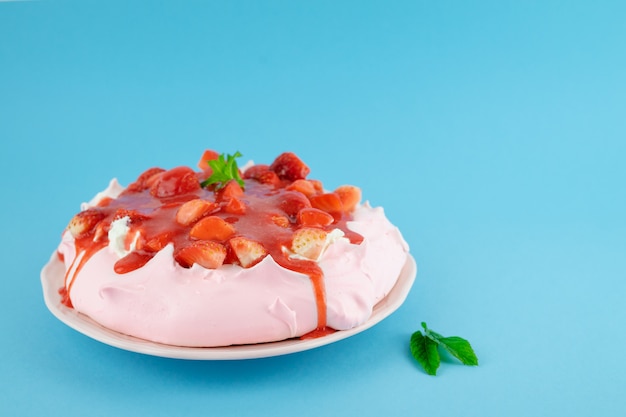 Pavlova red fruit cake on a blue table. Pastry concept.