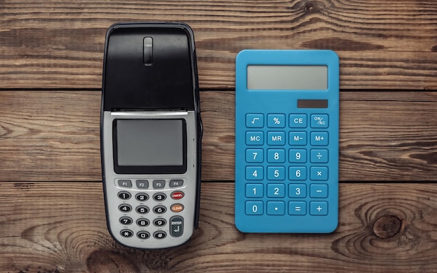 Payment POS terminal and calculatror on wooden table Top view