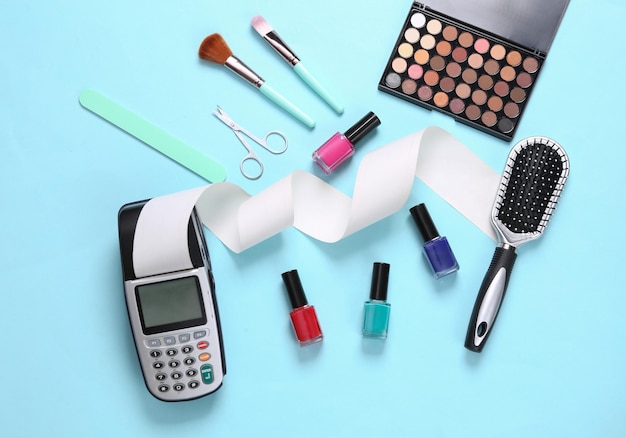 Payment pos terminal and makeup products on a blue background