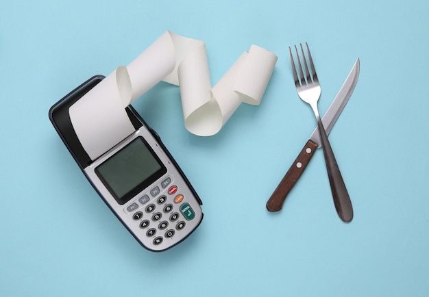 Payment terminal with a fork and knife on a blue background Payment at the restaurant