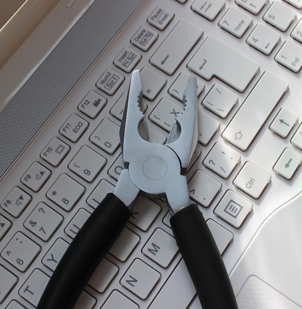 Photo pc support concept image metal pliers on laptop keypad closeup view