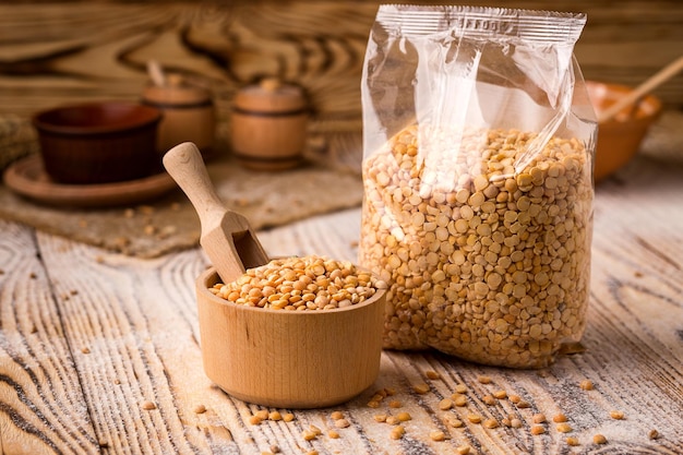 Pea groats in packing and bowl on a wooden background Healthy dietary cereals concept