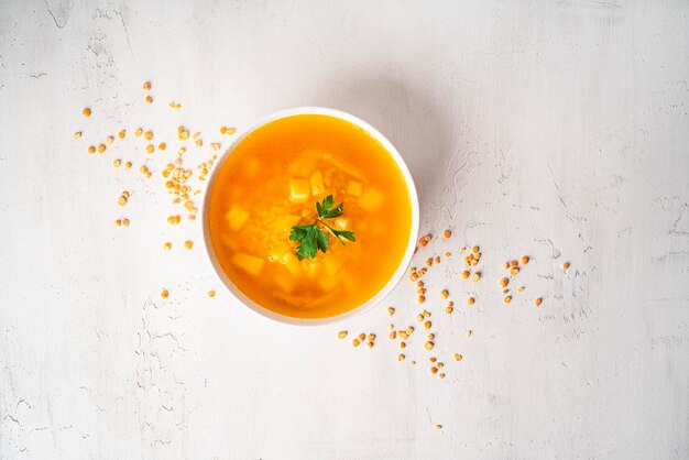 Pea soup on a light background. Pea soup in a white bowl. A bowl of soup. Parsley, pepper mixture, sauce, bread. High quality photo