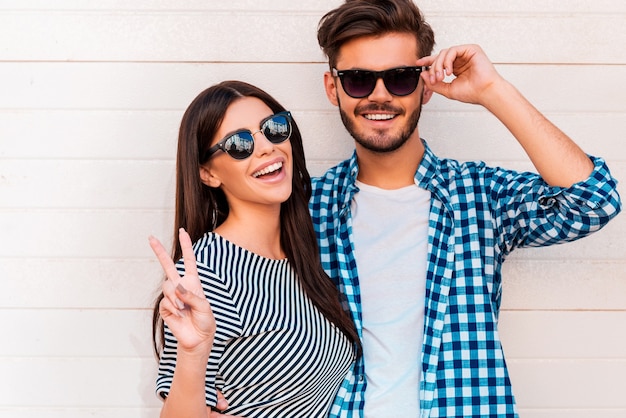 Peace out! Happy young loving couple looking at camera and smiling while standing outdoors