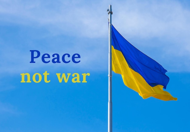 PEACE NOT WAR text on Ukrainian national flag flutters in the wind against the blue sky National symbol of ukrainian people blue and yellow No war War Protest against Russian invasion of Ukraine