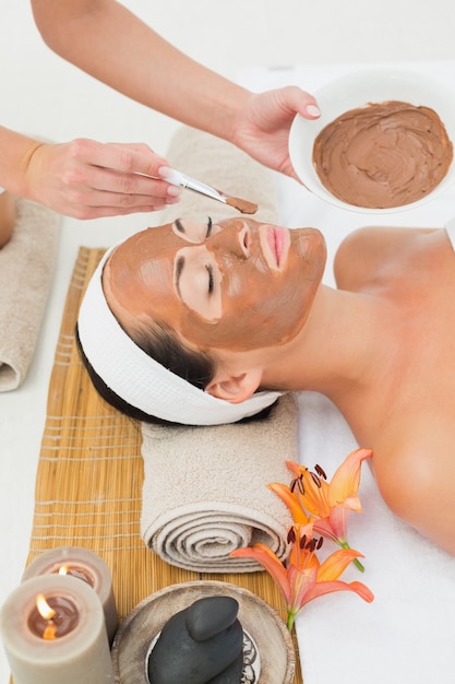 Peaceful brunette getting a mud treatment facial