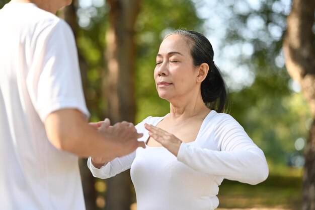 Peaceful senior people with closed eyes concentrating on breathing exercises in the park