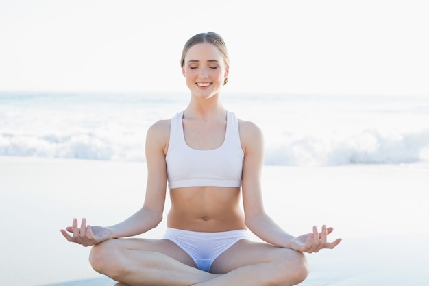 Peaceful smiling woman meditating on the beach