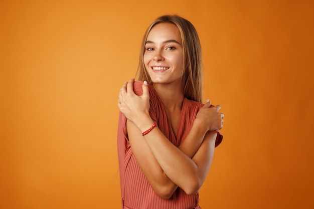 Peaceful young blonde woman holding hands on her chest