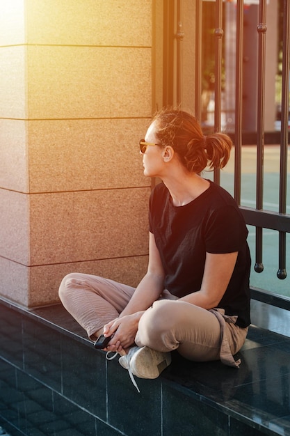 Peaceful young woman in sunglasses sitting cross legged on a marble