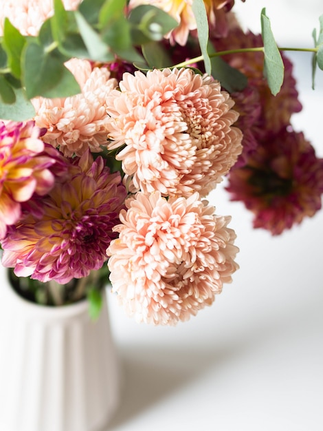 Peach asters and burgundy with yellow dahlias with eucalyptus branches in a vase. 