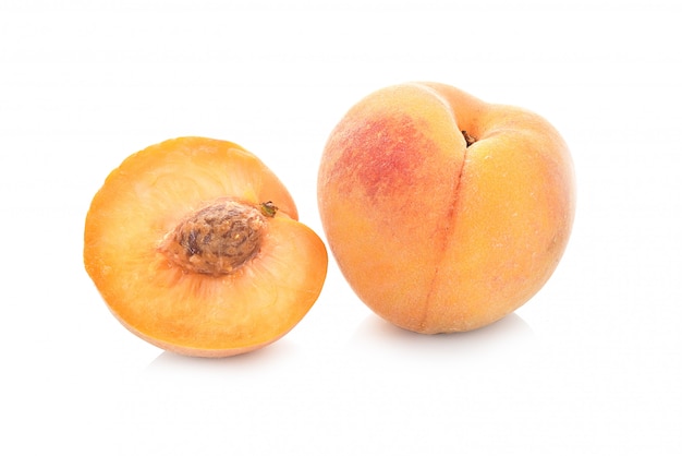 Peach fruit half with leaf isolated on white wall