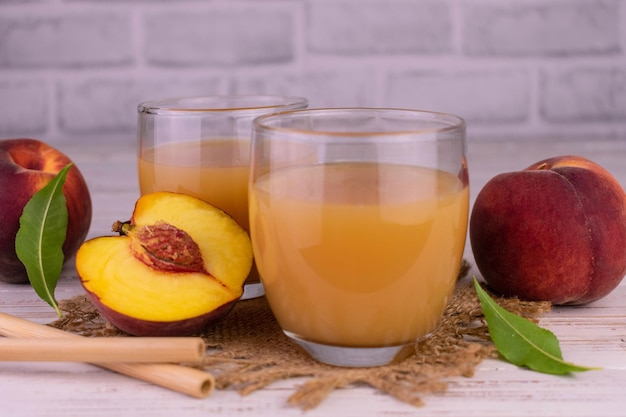 Peach juice in glasses on a white wooden background.