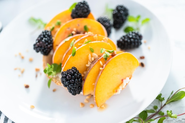 Peach ricotta toast garnished with blackberries on a white plate.