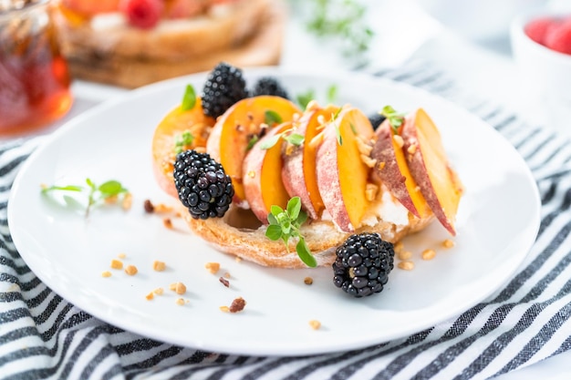 Peach ricotta toast garnished with blackberries on a white plate.