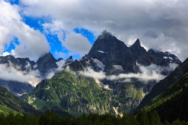 Peak of the mountain with glaciers against the background of clouds and sky